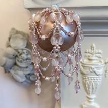 A pink bauble with a pink beaded bauble ornament cover.