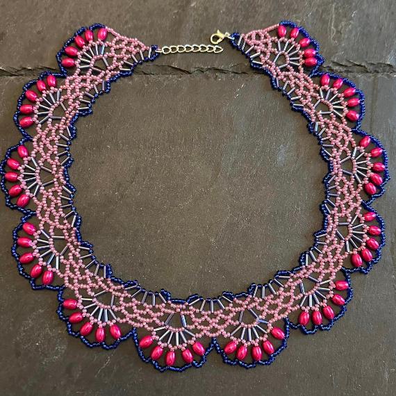 A lace collar necklace made from beads lying on a grey slate.