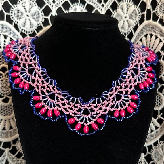 A lace collar necklace made from beads on a velvet stand.