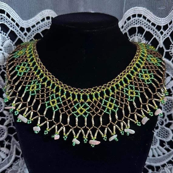 A lace collar necklace made from beads on a velvet stand.