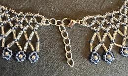 A close up photo of a lace necklace made from blue seed beads.