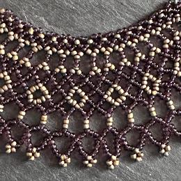 A close up photo of a lace necklace made from brown seed beads.