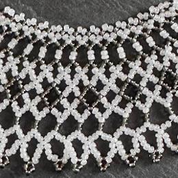 A close up photo of a white and grey beaded lace necklace.