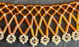 A close up photo of an orange beaded lace necklace.