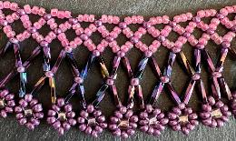 A close up view of a pink and purple beaded lace necklace.