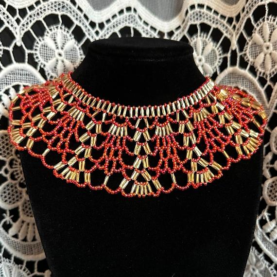 A lace collar necklace made from beads on a velvet stand.