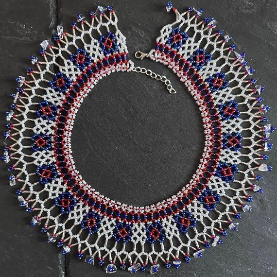 A lace collar necklace made from tiny beads lying on a grey slate.