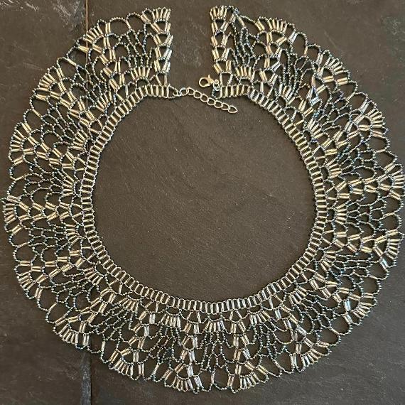 A lace collar necklace made from beads lying on a grey slate.