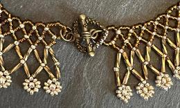 A close up photo of a bronze beaded collar necklace.